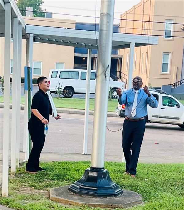 Mr. Prince showing a student how to properly place the US flag half staffed in remembrance of 9/11